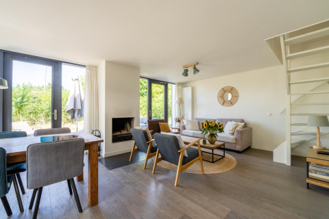 Lyst og moderne opholdsstue med spisebord, sofa og armstole i et feriehus i Holland.