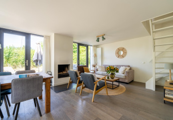 Salon lumineux et moderne avec salle à manger, canapé et fauteuils dans une maison de vacances aux Pays-Bas.