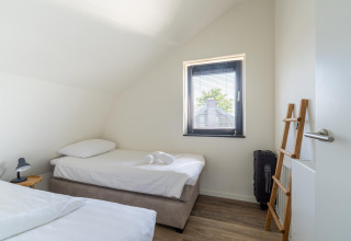 Helles Schlafzimmer im Ferienhaus Waterland für sechs Personen in den Niederlanden mit zwei Einzelbetten.