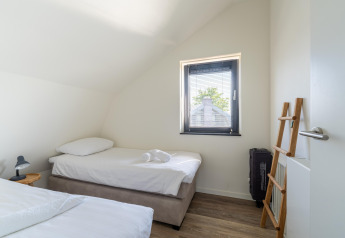 Bright, minimalist bedroom in Holiday home Waterland for six Person, Netherlands, with twin beds and window.