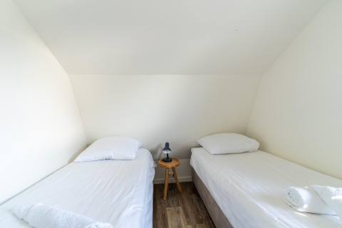 Helles Zimmer mit zwei Einzelbetten, weißer Bettwäsche und Nachttisch im Holiday home Waterland in den Niederlanden.
