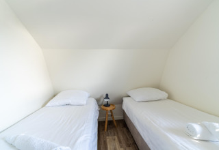Lichte kamer met twee aparte bedden, wit linnen en nachttafeltje in Holiday home Waterland Nederland.
