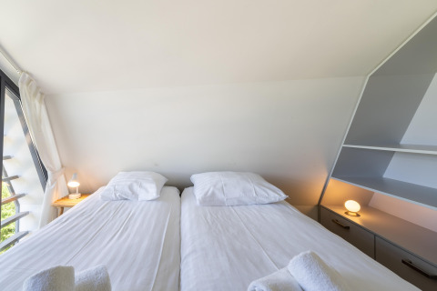 Helles Schlafzimmer mit zwei Einzelbetten, weißen Laken und modernen Lampen in einem Pod in Waterland, Niederlande.