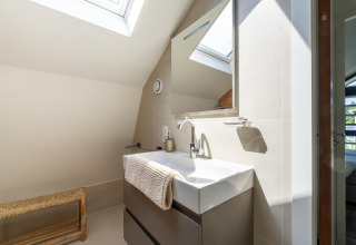Modernes Badezimmer mit Dachfenster, Waschbecken und Spiegel im Holiday Home Waterland für sechs Personen.