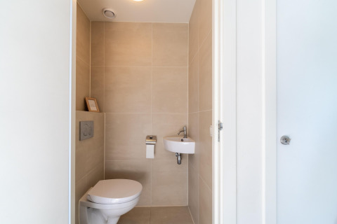 Bagno moderno e compatto con WC sospeso e piccolo lavandino nella casa vacanze Waterland in Olanda.