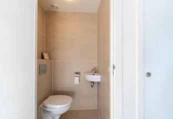 Modern, compact toilet met muurhangend toilet en kleine lavabo in vakantiehuis Waterland, Nederland.