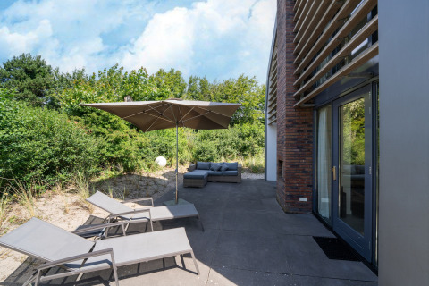 Terraza exterior en Holiday home «Waterland for six Person» en los Países Bajos con tumbonas y sombrilla.