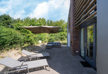 Buitenterras bij Holiday home «Waterland for six Person» in Nederland met ligstoelen en parasol.