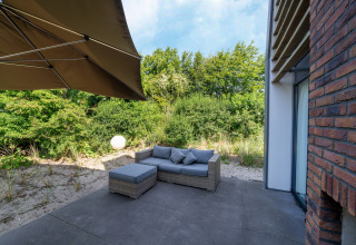 Patio esterno presso Holiday home Waterland for six Person nei Paesi Bassi con divano e ombrellone.