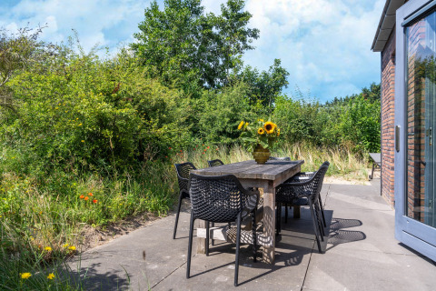 Udendørs spiseområde ved Holiday home Waterland for seks personer i Holland, med træbord og blomster.