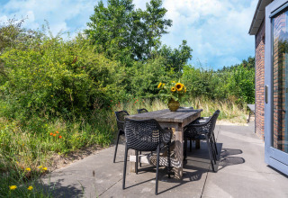 Udendørs spiseområde ved Holiday home Waterland for seks personer i Holland, med træbord og blomster.
