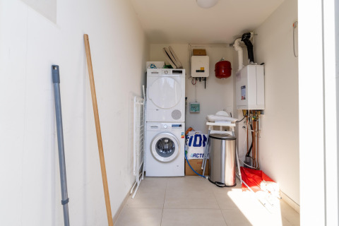 Lavanderia con lavatrice, asciugatrice, pattumiera e articoli per la pulizia in casa vacanze olandese.