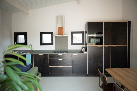 Cocina moderna en Sea Lodges Zandvoort 3, Países Bajos, con gabinetes oscuros y mesa de madera.