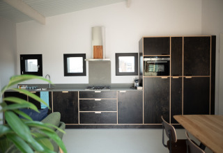 Cocina moderna en Sea Lodges Zandvoort 3, Países Bajos, con gabinetes oscuros y mesa de madera.