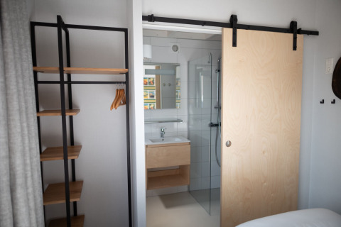 Habitación moderna en Sea Lodges «Zandvoort 3», Países Bajos, con puerta corredera y vestidor abierto.