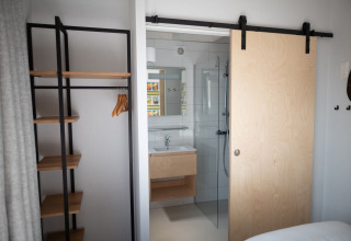 Habitación moderna en Sea Lodges «Zandvoort 3», Países Bajos, con puerta corredera y vestidor abierto.