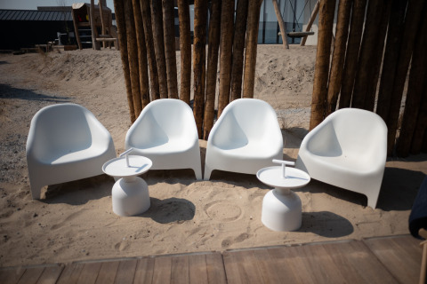 Cuatro sillas blancas modernas y dos mesas pequeñas en la arena en Sea Lodges ‘Zandvoort 3’ en los Países Bajos.