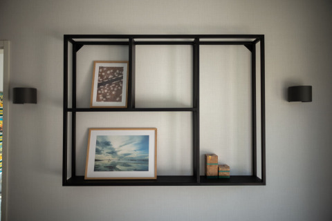 Estante moderno negro montado en la pared con cuadros y cajas, fotografiado en Sea Lodges Zandvoort 3 en Holanda.