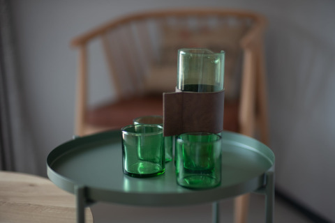 Vasos verdes y una jarra sobre una mesa redonda con una silla de madera al fondo, en Sea Lodges Zandvoort 3, Países Bajos.