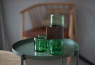 Vasos verdes y una jarra sobre una mesa redonda con una silla de madera al fondo, en Sea Lodges Zandvoort 3, Países Bajos.