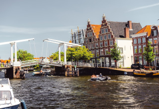 Foto de un canal holandés, puente tradicional y edificios históricos en Zandvoort, Países Bajos, en un día soleado.