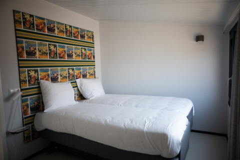 Dormitorio en Sea Lodges Zandvoort 1 en los Países Bajos con dos camas individuales y arte mural colorido.
