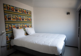 Schlafzimmer in Sea Lodges Zandvoort 1 in den Niederlanden mit zwei Betten und farbenreicher Tapete.