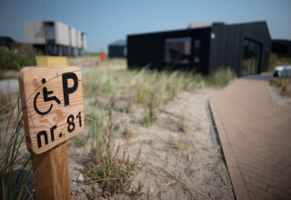 Señal de aparcamiento accesible en Sea Lodges Zandvoort 1 con camino y césped de dunas en los Países Bajos.