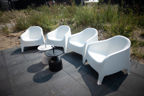 Cuatro sillas blancas de exterior y dos mesas pequeñas en la terraza de Sea Lodges Zandvoort 1 en Holanda.