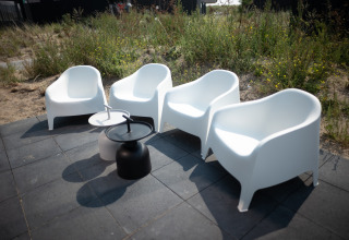 Vier witte stoelen en twee kleine tafels staan op het terras van Sea Lodges Zandvoort 1 in Nederland.