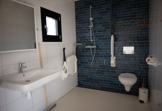 Baño accesible con ducha, inodoro suspendido y barras de apoyo en Sea Lodges Zandvoort 1, Países Bajos.