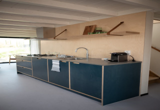 Cocina moderna con gabinetes azules y estante de madera en Sea Lodges Zandvoort 4, casa de playa en Países Bajos.