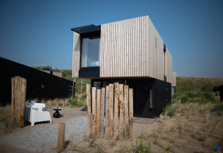 Casa de playa moderna en Sea Lodges «Zandvoort 4», Países Bajos, con fachada de madera y dunas alrededor.