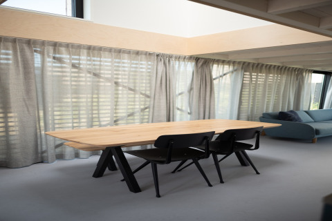 Lichte, moderne eetruimte met houten tafel en zwarte stoelen in Sea Lodges Zandvoort 4 aan het strand in Nederland.