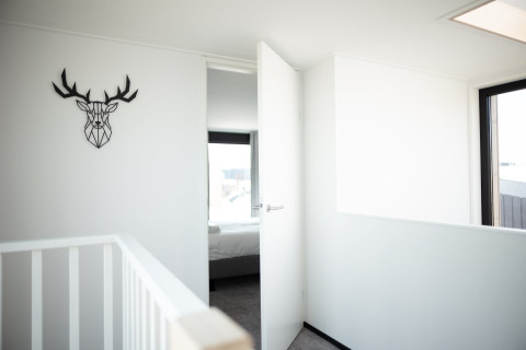 Licht en modern interieur van Sea Lodges Zandvoort 4 strandhuis in Nederland, met een hert aan de muur.