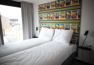 Dormitorio con dos camas individuales en Sea Lodges Zandvoort 4, decoración moderna y papel tapiz colorido.