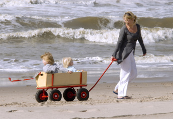 Eine Frau zieht zwei Kinder in einem Wagen am Strand bei Sea Lodges Zandvoort in den Niederlanden.