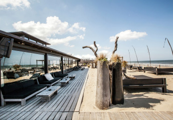 Terrasse des Sea Lodges Zandvoort 4 in den Niederlanden mit Sitzgelegenheiten, Meerblick und Strand.