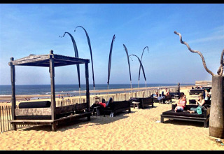 Vista en la playa de Sea Lodges Zandvoort, Países Bajos, con sillones, personas y el mar al fondo.