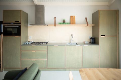Cocina moderna de casa de playa con gabinetes de madera, estufa de gas y repisa en Zandvoort, Países Bajos.