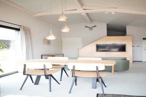 Salón luminoso y moderno con mesa de comedor y sofá verde en Sea Lodges Zandvoort 3, Países Bajos.