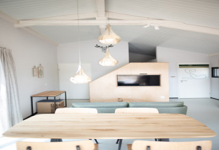 Interior luminoso y moderno de Sea Lodges Zandvoort 3 en Países Bajos, con mesa, sofá y televisor.