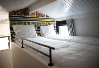 Dormitorio tipo altillo moderno con dos camas individuales y decoración de cómic en Sea Lodges Zandvoort, Países Bajos.