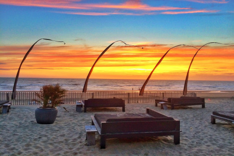 Glamping aan zee bij zonsondergang, gezellige bedden en prachtig zicht op het strand en de horizon.