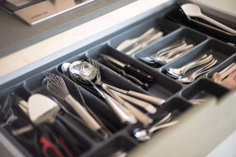Cajón de cocina abierto con organizador de cubiertos, contiene cucharas, tenedores, cuchillos y utensilios.
