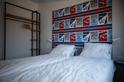Dormitorio moderno en Sea Lodges Zandvoort 9 con cama doble, pared de carteles coloridos y armario abierto.