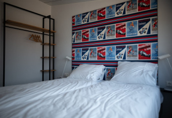 Modernes Schlafzimmer in Sea Lodges Zandvoort 9 mit Doppelbett, bunter Posterwand und offenem Kleiderschrank.