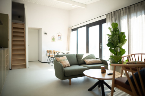 Sala moderna y luminosa en Sea Lodges Zandvoort 9 en los Países Bajos, con sofá, comedor y grandes ventanas.