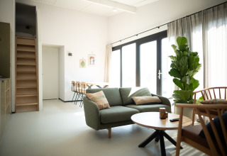 Sala moderna y luminosa en Sea Lodges Zandvoort 9 en los Países Bajos, con sofá, comedor y grandes ventanas.