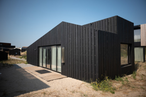 Moderna casa de playa negra en Sea Lodges Zandvoort 9, Países Bajos, rodeada de arena y dunas.